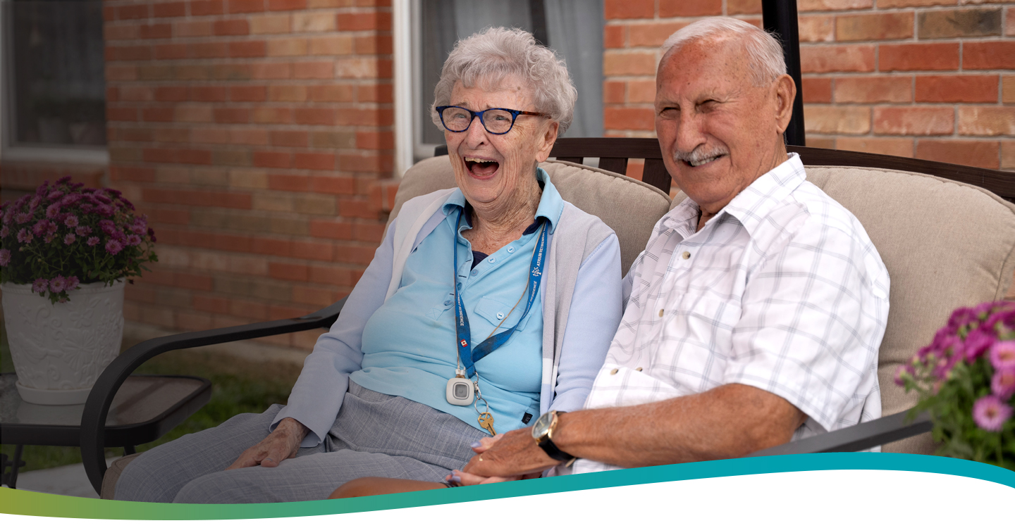 Two residents sharing laughter on the patio at Atrium Retirement Residence in Orillia.