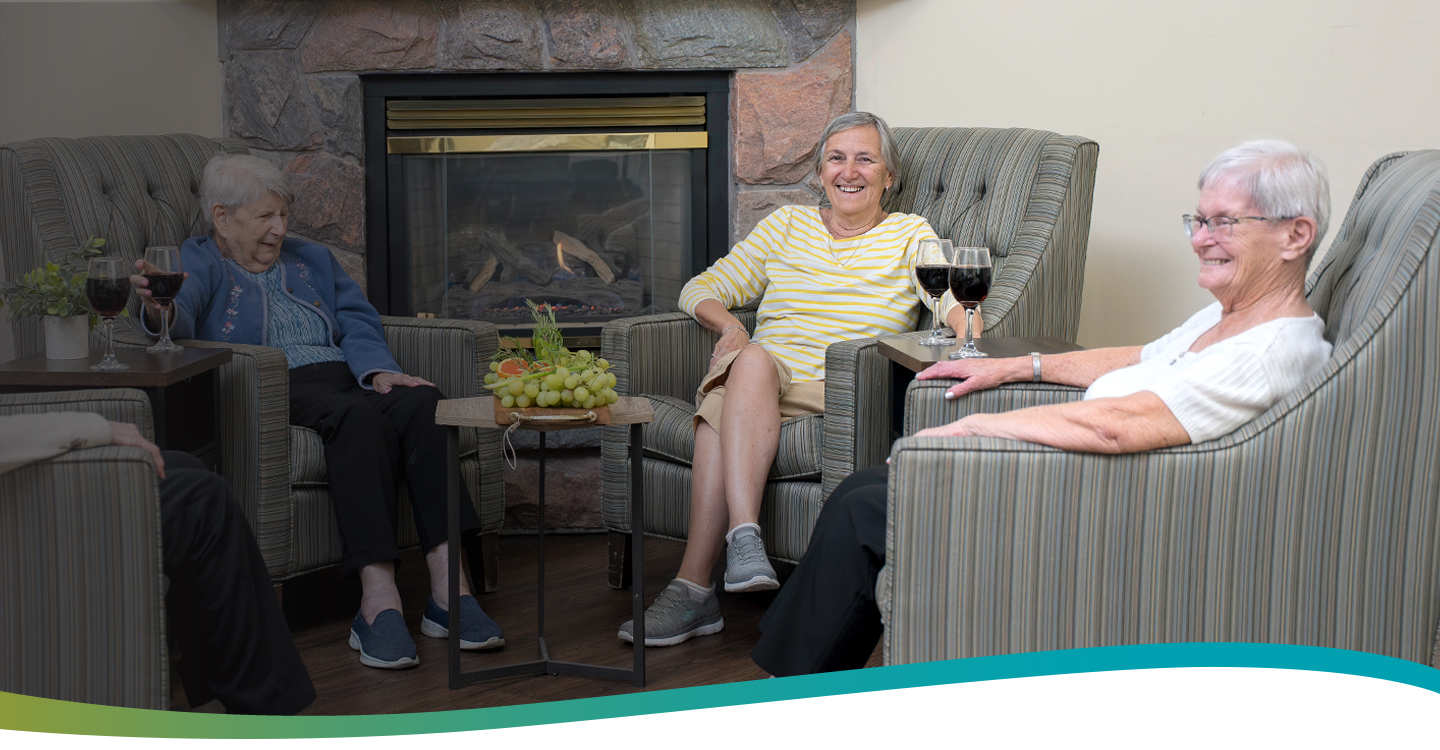 Group of residents enjoying wine and cheese by the fireplace at Atrium Retirement Residence in Orillia